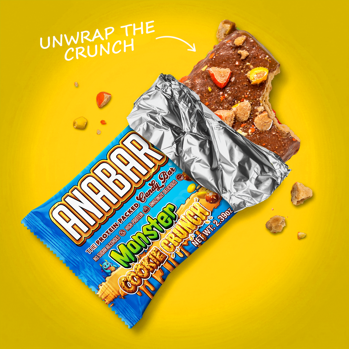 A partially unwrapped Monster Cookie Crunch protein bar with cookie and candy toppings and a bite taken out of one end, set against a yellow background.