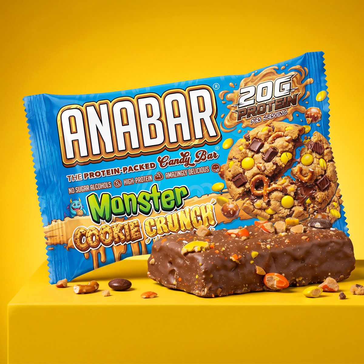 A Monster Cookie Crunch protein bar rests in front of its bright blue wrapper, which displays a large broken cookie filled with chocolate chunks, pretzels, and candy pieces.