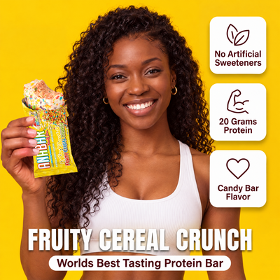 A smiling woman holds a The Anabar Fruity Cereal Crunch protein bar against a yellow background, with text icons noting no artificial sweeteners and 20g protein.