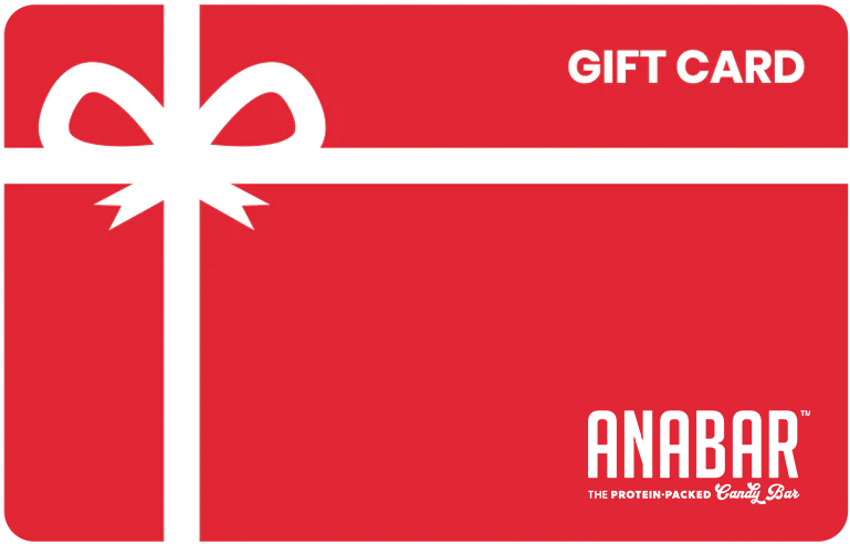 A red Anabar Gift Card features a white ribbon on the left, with "GIFT CARD" at the top right and "ANABAR The Protein-Packed Candy Bar" at the bottom. Ideal for any occasion, these gift cards offer convenient email delivery, simplifying and enhancing your gifting experience.